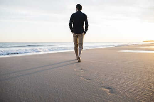 young man walking on beach after a heroin detox center