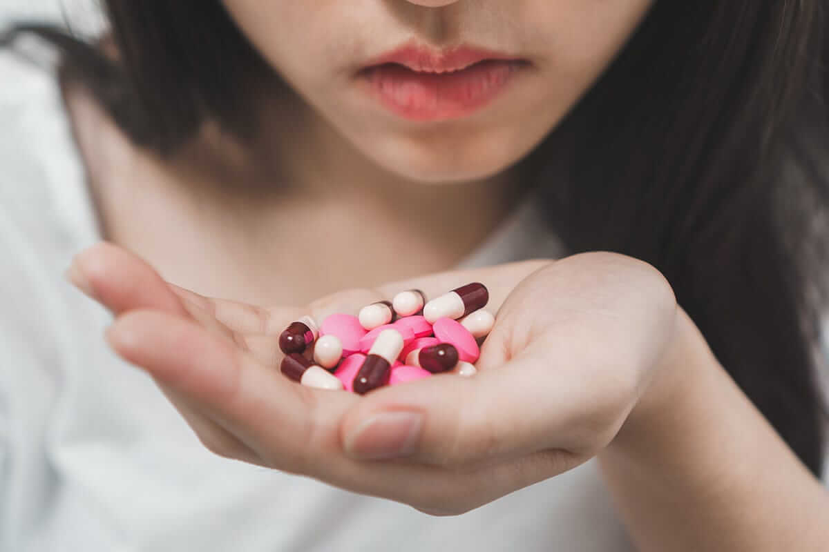 woman holds handful of multiple pills and contemplates xanax addiction treatment