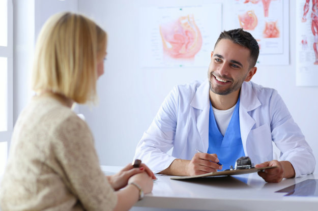 Handsome doctor is talking with young female patient and making notes while sitting in his office how to detox from alcohol