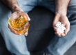 Man holding a glass of alcohol and xanax in the other hand